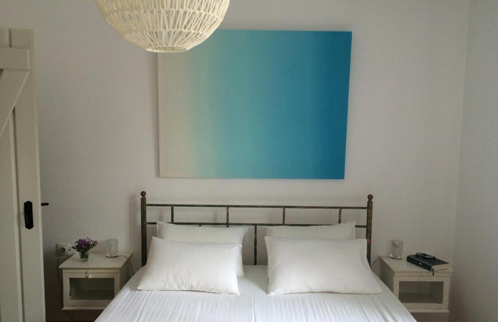 a bedroom with a bed with white pillows and a blue painting at Ferienhaus Triandafilo in Pythagoreio