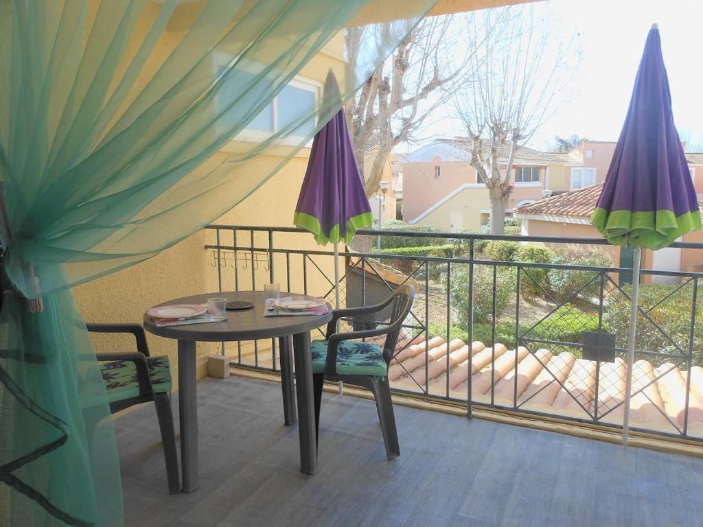 - une table et des chaises sur un balcon avec des parasols dans l'établissement APPT 2 PIECES 28m2 + LOGGIA 7m2 REF 4005, à Le Castellas