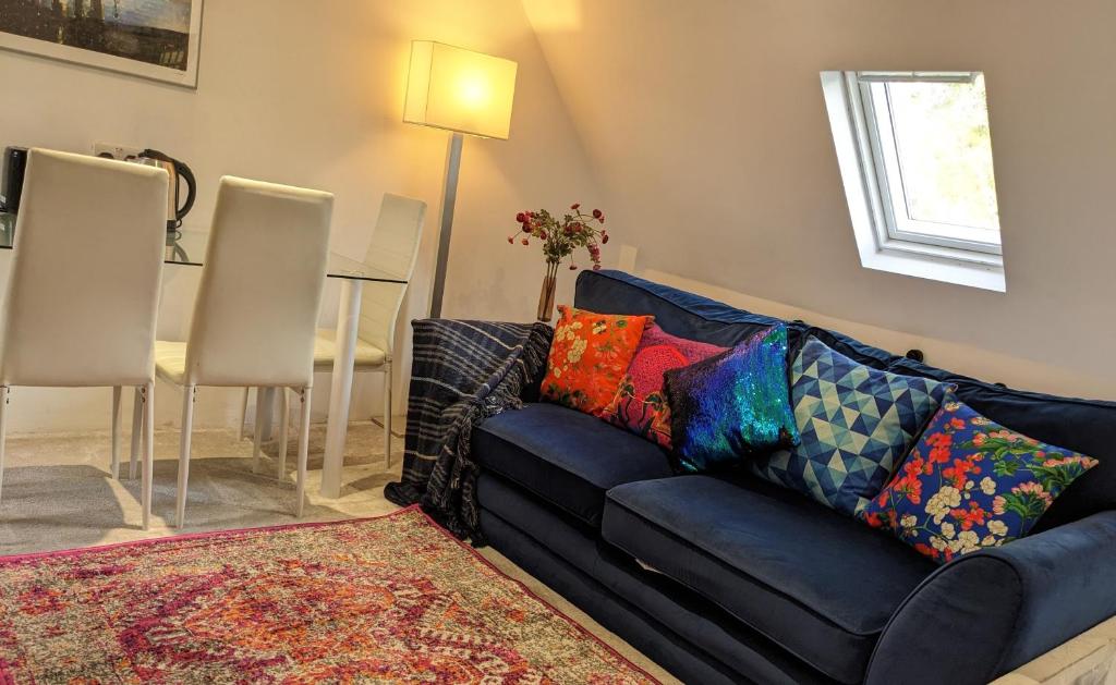 a living room with a blue couch with colorful pillows at Small apartment in the heart of Selsdon! in Addington