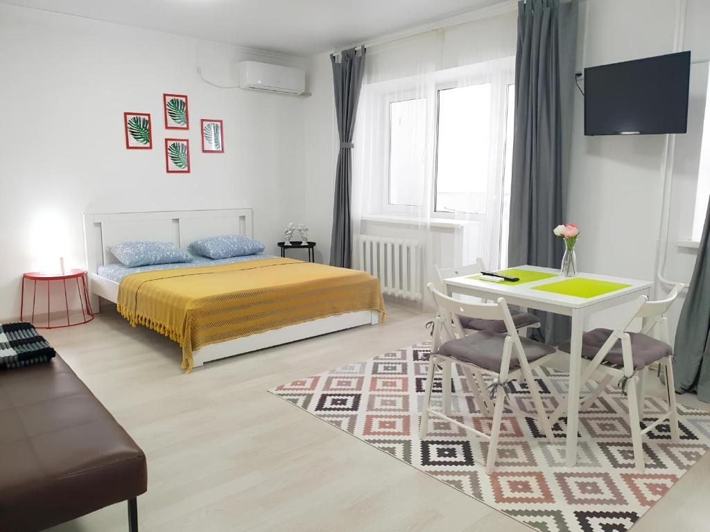 a bedroom with a bed and a table and chairs at Милая Студия 2 in Atyrau