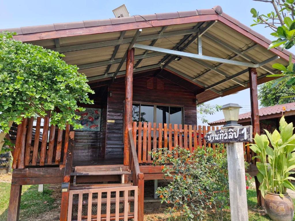 Cabaña de madera con porche y cartel en Yungthong Baan Suan Resort, en Ban Ko