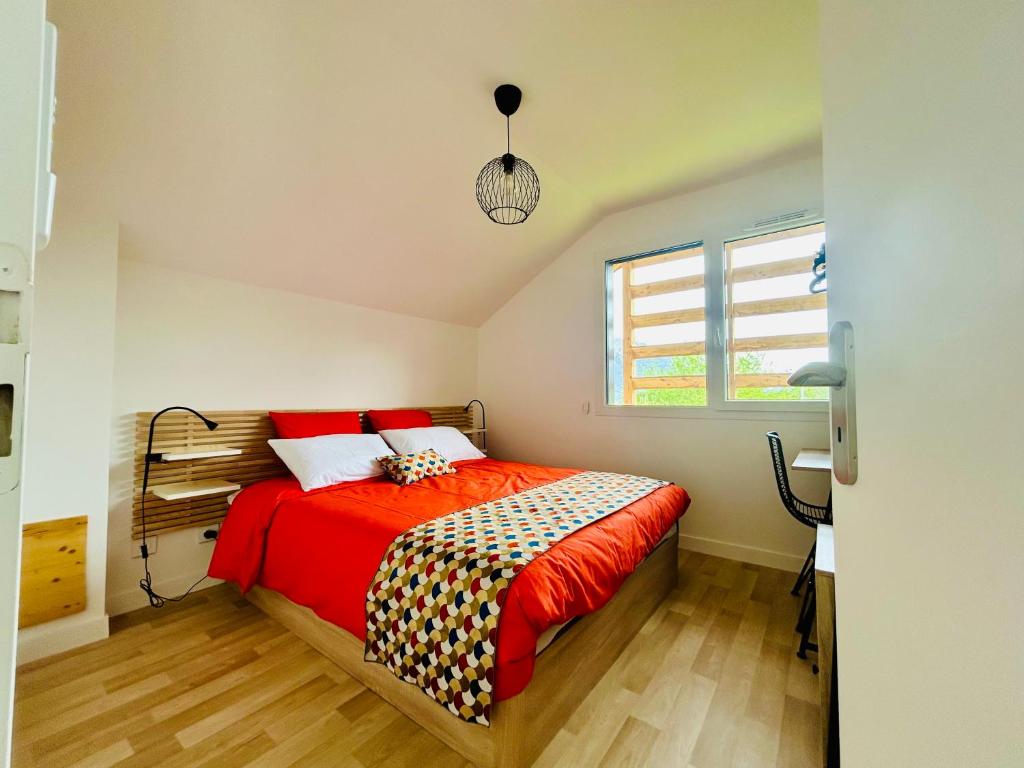 Schlafzimmer mit einem Bett mit einer roten Bettdecke in der Unterkunft Gîte de la Source - CLG Savoie - Vélo tourisme - 2CH - 2SDB 