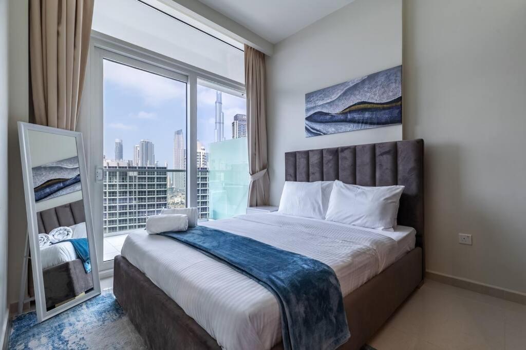 a bedroom with a bed and a large window at Goldbest-Reva Burj Khalifa view in Dubai
