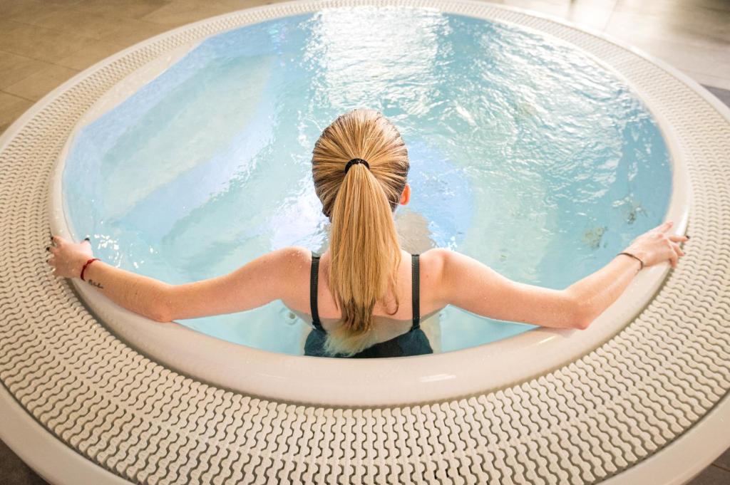 a woman sitting in a pool in a circular swimming pool at Kyriad Prestige Residence & Spa Cabourg-Dives-sur-Mer in Dives-sur-Mer