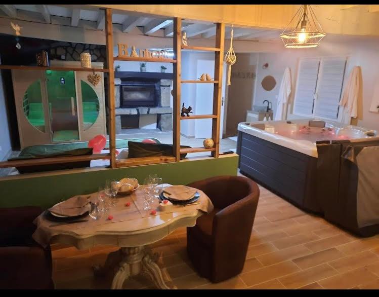 eine Küche mit einem Tisch und einer Badewanne in der Unterkunft Le Petit Paradis de Marcelise in Le Ponchel