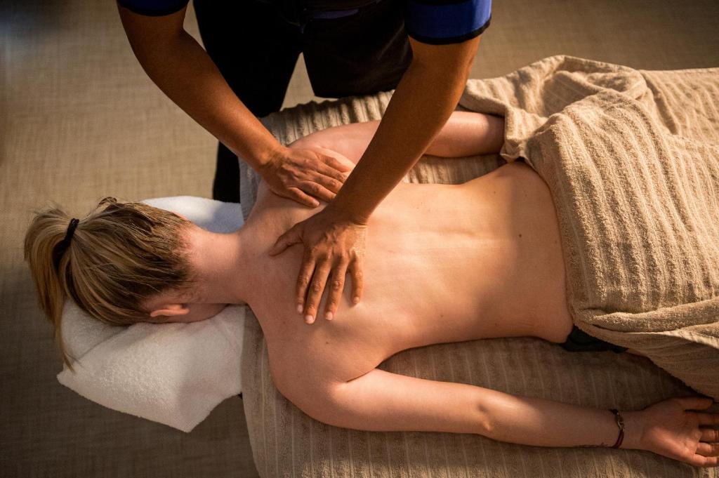 a woman getting a back massage from a therapist at Kyriad Prestige Residence & Spa Cabourg-Dives-sur-Mer in Dives-sur-Mer
