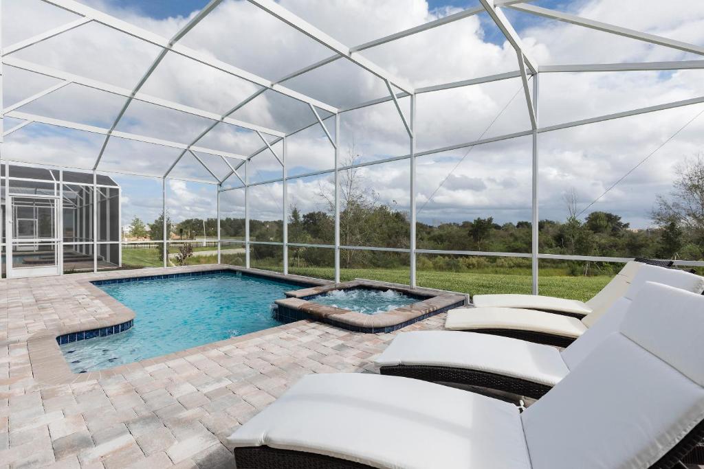a swimming pool in a glass house with a patio and chairs at 1509 MC - Exquisite 8BR Villa with Pool Games in Davenport
