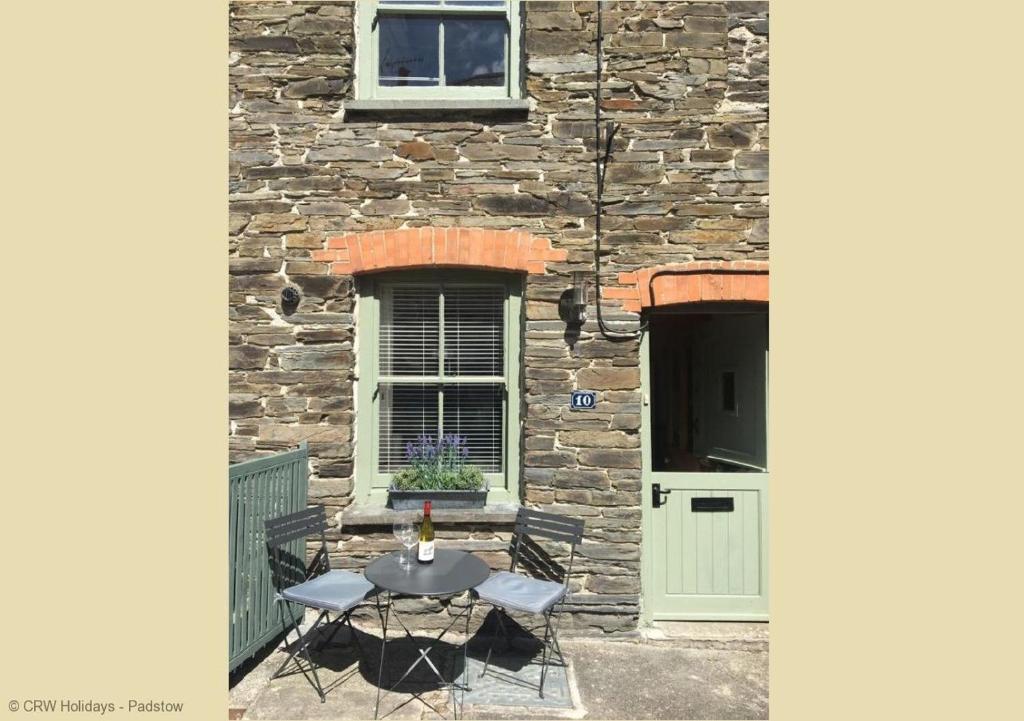 a table and chairs in front of a building with a door at 10 Mill Road in Padstow