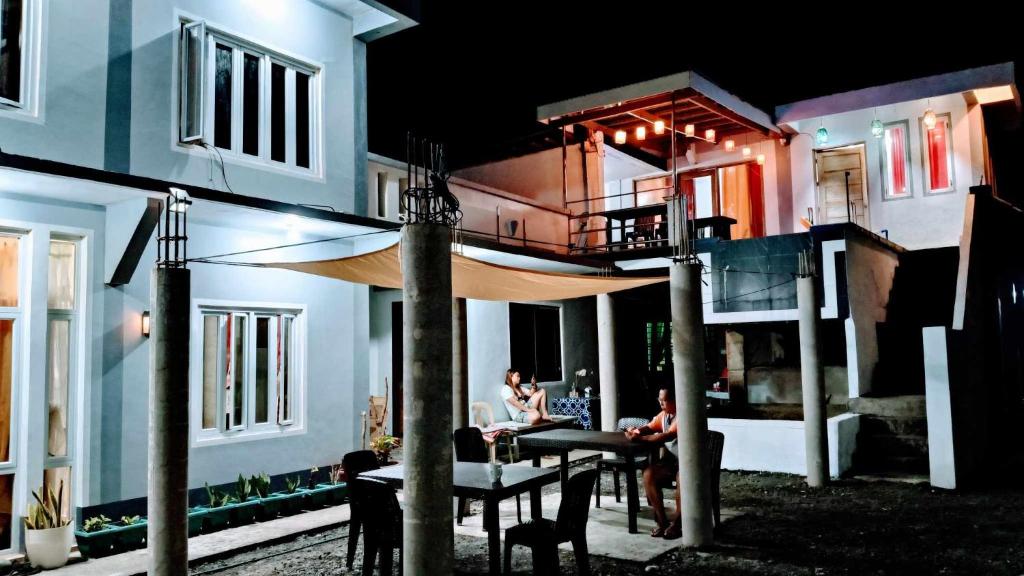 ein Haus mit Leuten, die nachts draußen an Tischen sitzen in der Unterkunft Private Home Ocean View Resort Talaonga in Sorsogon
