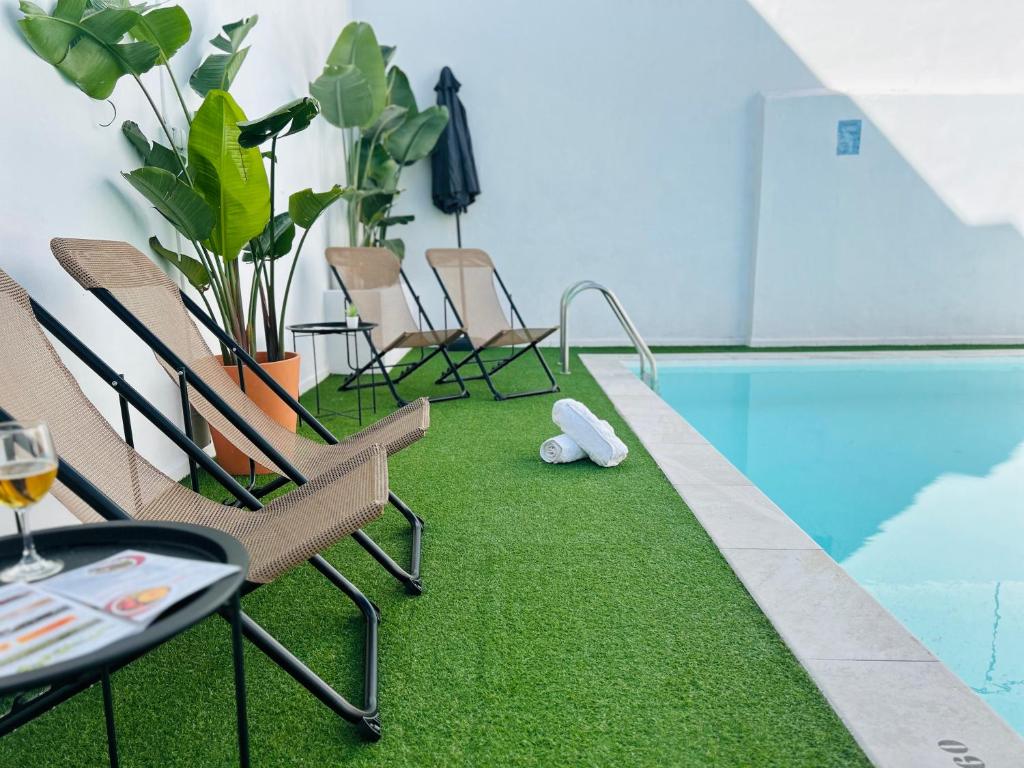 una piscina con sillas y una mesa con una copa de vino en Apartamento Plaza, en Castilleja de la Cuesta