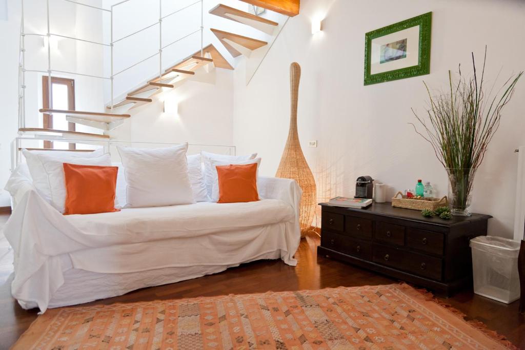 un sofá blanco con almohadas naranjas en la sala de estar. en Appartamento San Michele en Milán