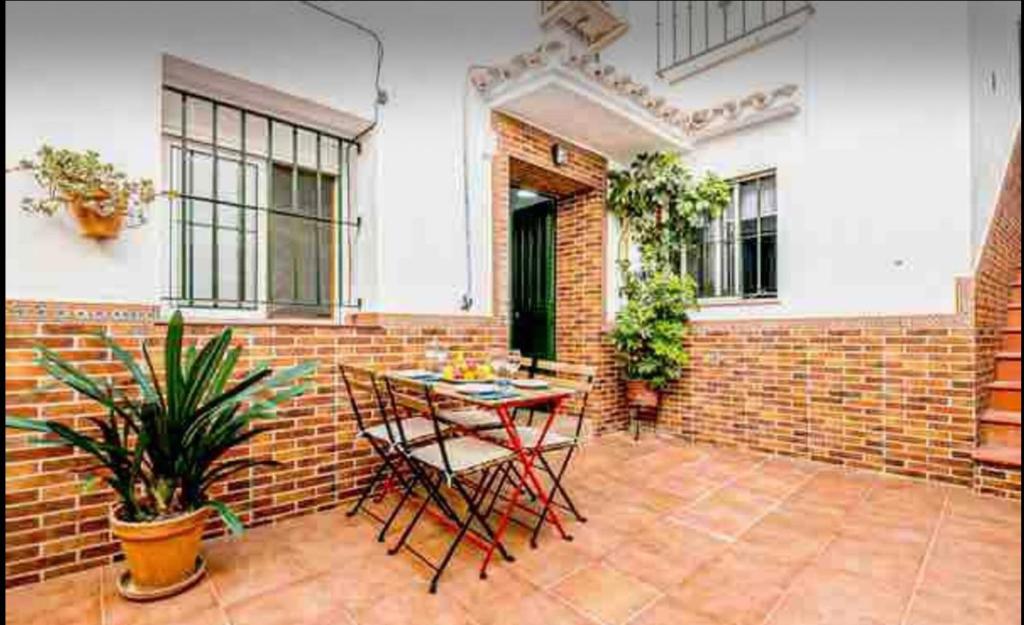 patio con mesa, sillas y pared de ladrillo en Casa los Geranios, en Arcos de la Frontera