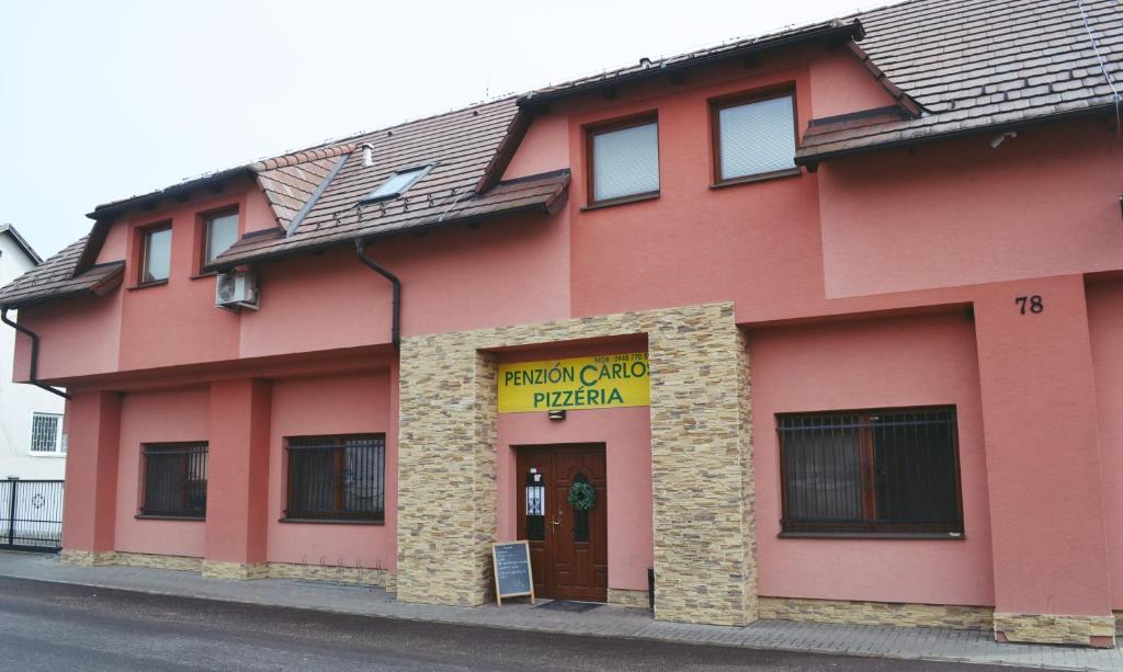 Penzion Carlos في Podlužany: مبنى احمر عليه علامة صفراء