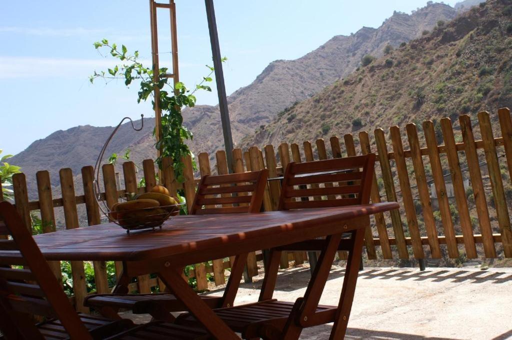 a wooden table with a bowl of fruit on top of a fence at Vivienda Vacacional Cuenca de Liria in Hermigua