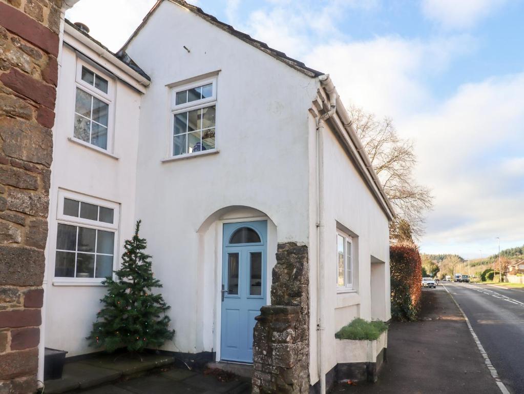 ein weißes Haus mit einer blauen Tür und einem Weihnachtsbaum in der Unterkunft Granary Studio in Gloucester