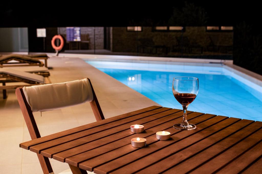 a glass of wine sitting on a wooden table next to a swimming pool at Silver Cozy Getaway - 3 Pearls Pool Retreat in Dhémbla