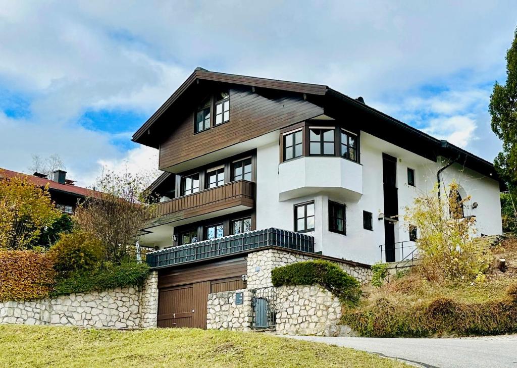 Cette grande maison blanche est dotée d'un mur en pierre. dans l'établissement Ferienwohnung Suite-Mathilda, à Reit im Winkl