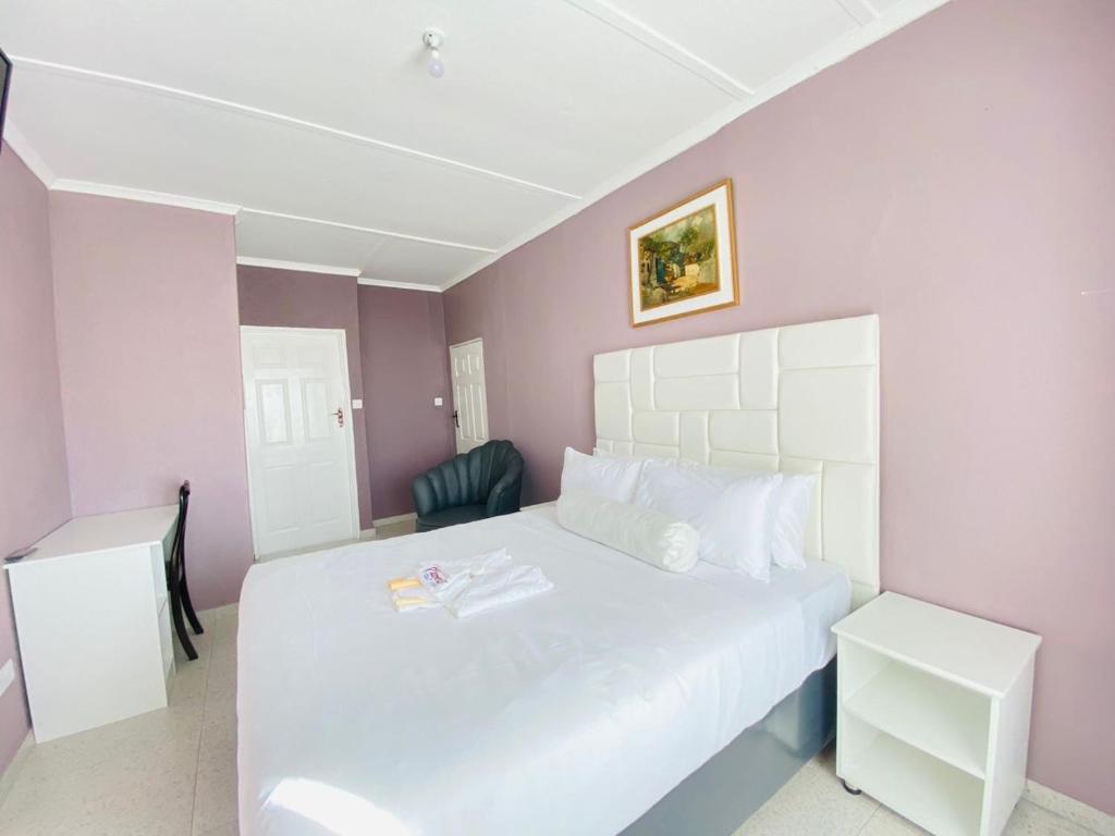 um quarto com uma cama branca e paredes roxas em Cumberland Guest Lodge em Bulawayo