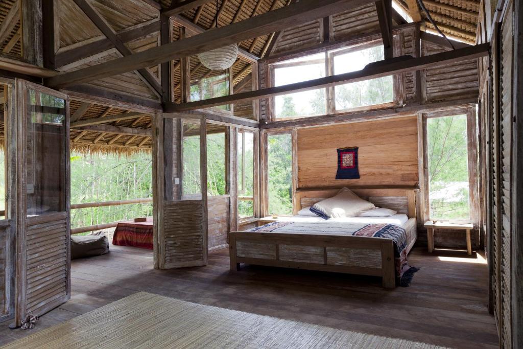 una camera da letto in una casa sull'albero con un letto e finestre di MaoMeno Yoga Resort a Gili Meno