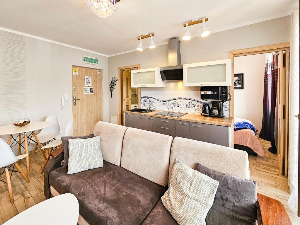 a living room with a couch and a kitchen at visit baltic - Kwartał Róży Wiatrów apartament SK30 z parkingiem in Świnoujście