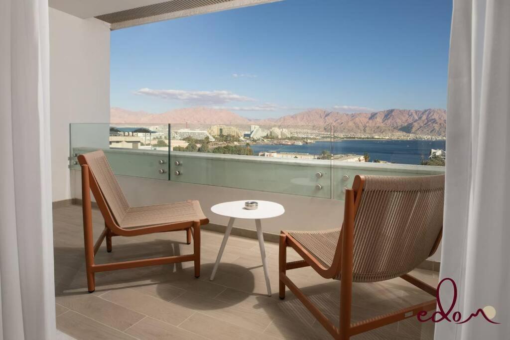 uma varanda com 2 cadeiras, uma mesa e uma vista em דירת 2 חדרי שינה עם נוף מדהים לים - By Edom em Eilat