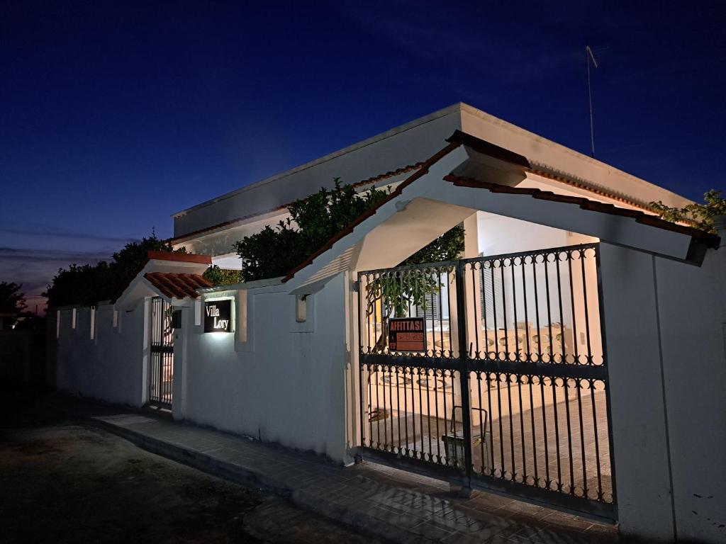 uma casa branca com um portão à noite em Villa Lory Torre Ovo em Torre Ovo