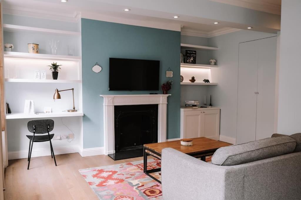 uma sala de estar com um sofá, uma televisão e uma lareira em Sapphire Sanctuary em Londres