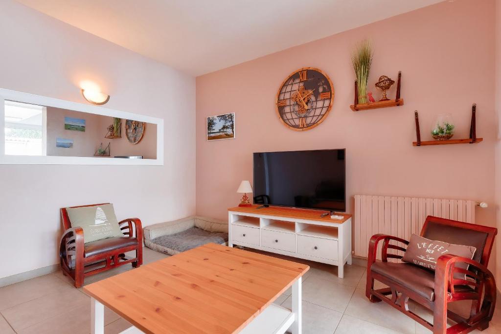 sala de estar con TV, mesa y sillas en Découverte des Sables d'Olonne en famille, en Les Sables-dʼOlonne