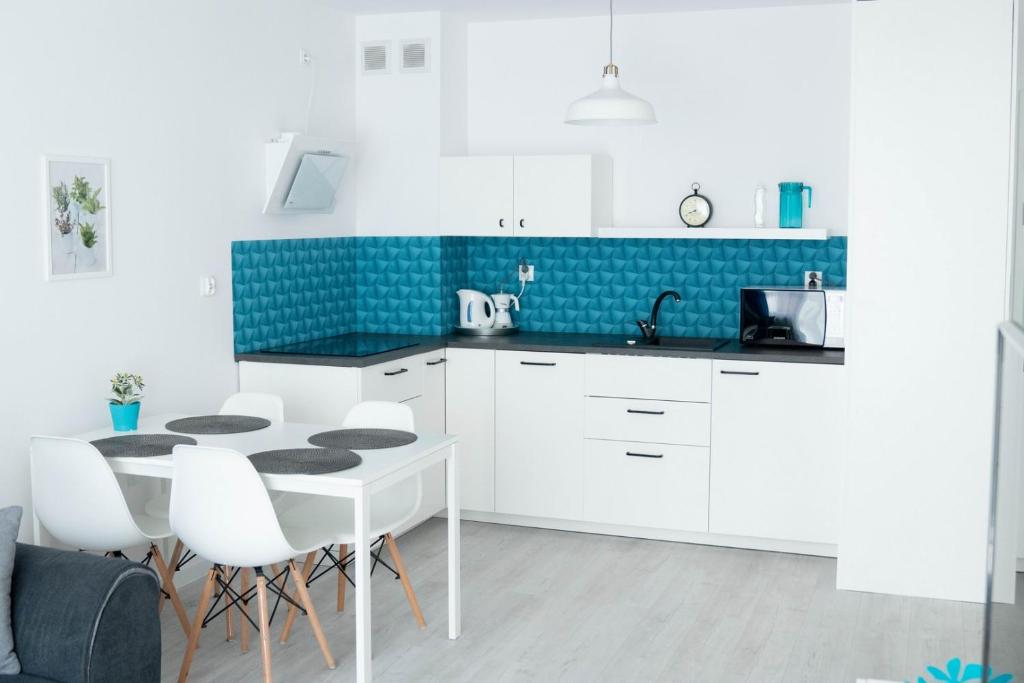 a kitchen with white cabinets and a table and chairs at Bliżej Morza Apartament 57 in Kołobrzeg