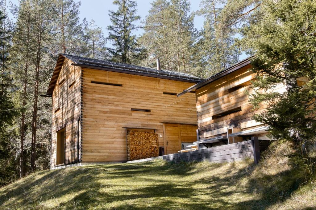 a wooden house in the woods with a yard at Mountain Lodge Tamersc in San Vigilio Di Marebbe