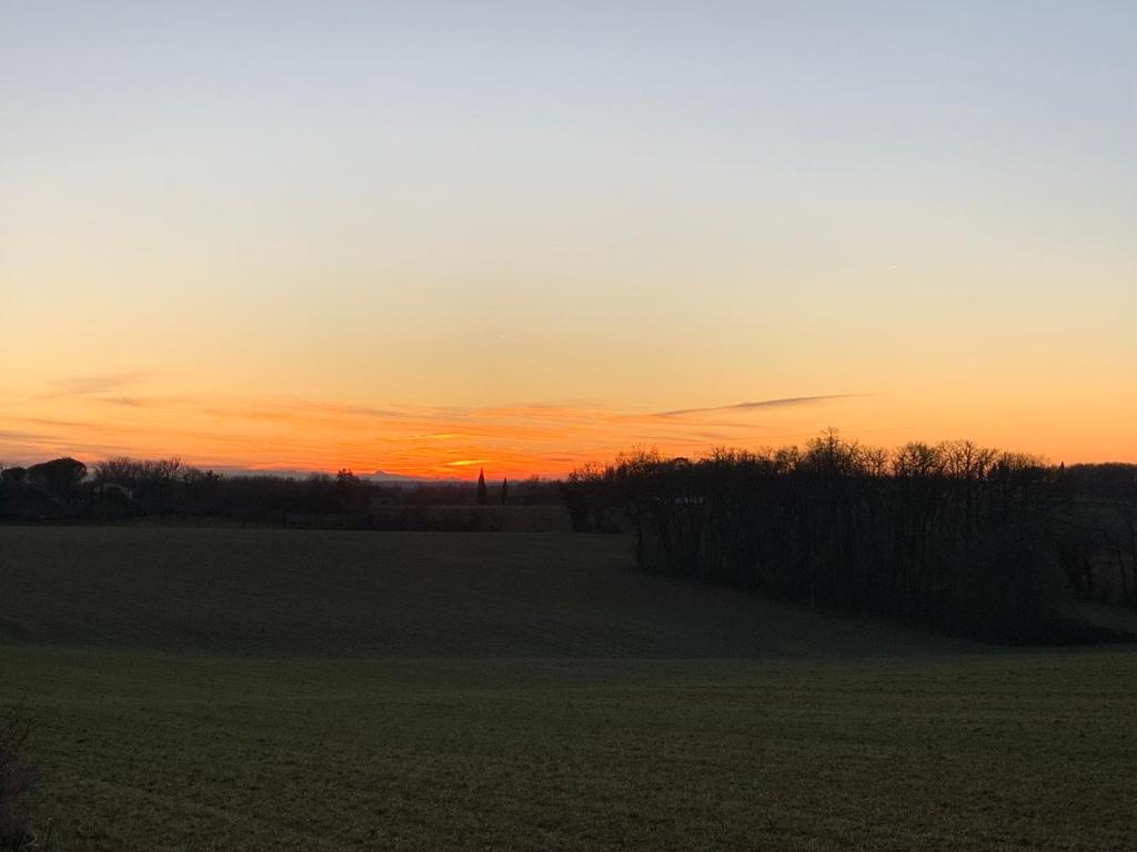 a sunset in a field with the sun setting at Gîte au calme, à la campagne in Magrin