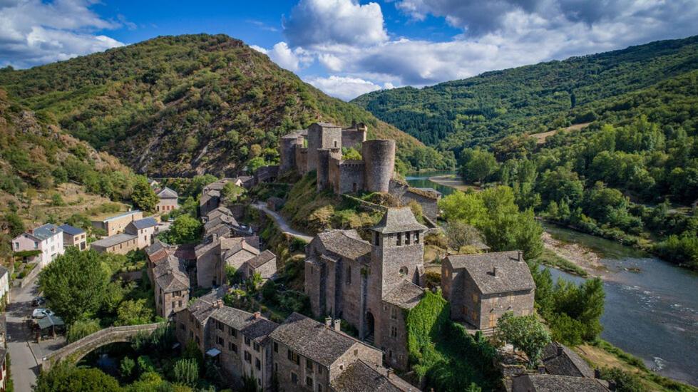 un viejo castillo en una colina junto a un río en Hôtel Restaurant Le Relays du Chasteau - Logis Hôtel, en Brousse-le-Château