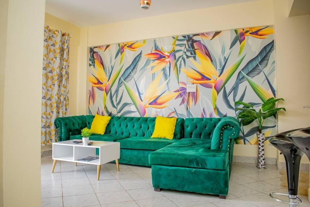 a green couch in a living room with a painting at Mogul's Palace (3 beds) Thika town in Thika