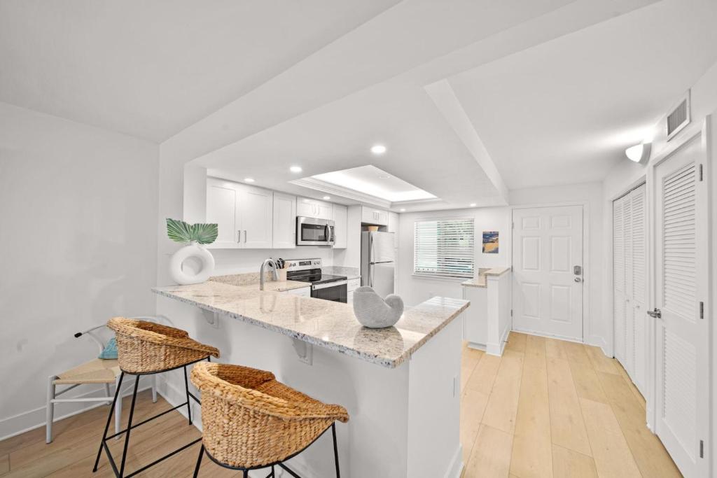 a kitchen with white cabinets and a counter with stools at Loggerhead Cay #401 in Sanibel