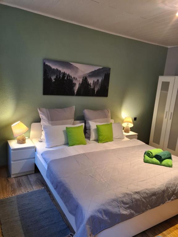 una camera da letto con un grande letto bianco con cuscini verdi di Waldblick Ferienwohnungen a Bonndorf im Schwarzwald