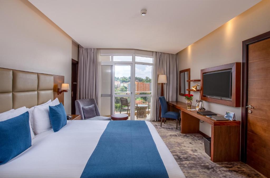 カンパラにあるGolden Tulip Canaan Kampalaのベッドとテレビが備わるホテルルームです。