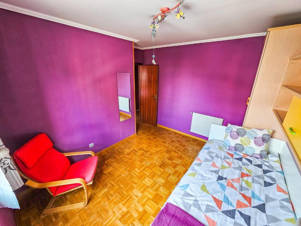um quarto com paredes roxas e uma cama e uma cadeira em 3 large room modern flat with private parking em Oviedo