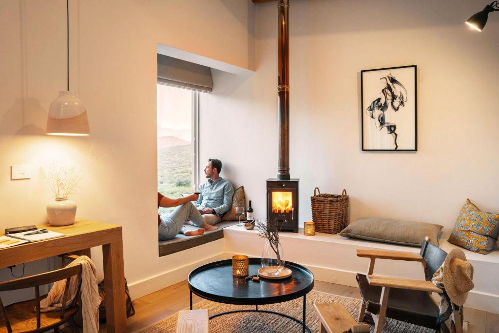 a man sitting in a living room with a fireplace at Simbavati Cederberg Ridge in Clanwilliam