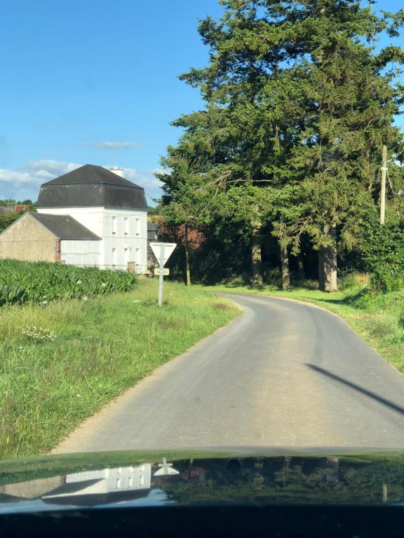 une route vide avec une maison blanche et des arbres dans l'établissement La Longère, à Brectouville