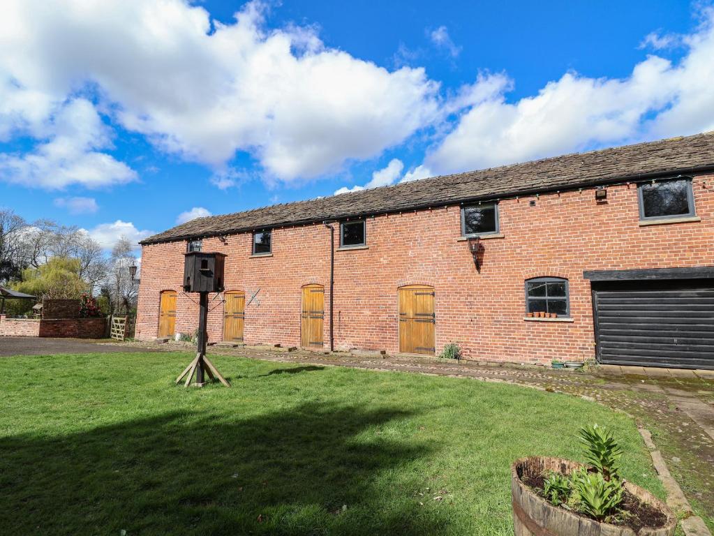 an old brick building with yellow doors and a grass yard at Lake View Barn in Macclesfield