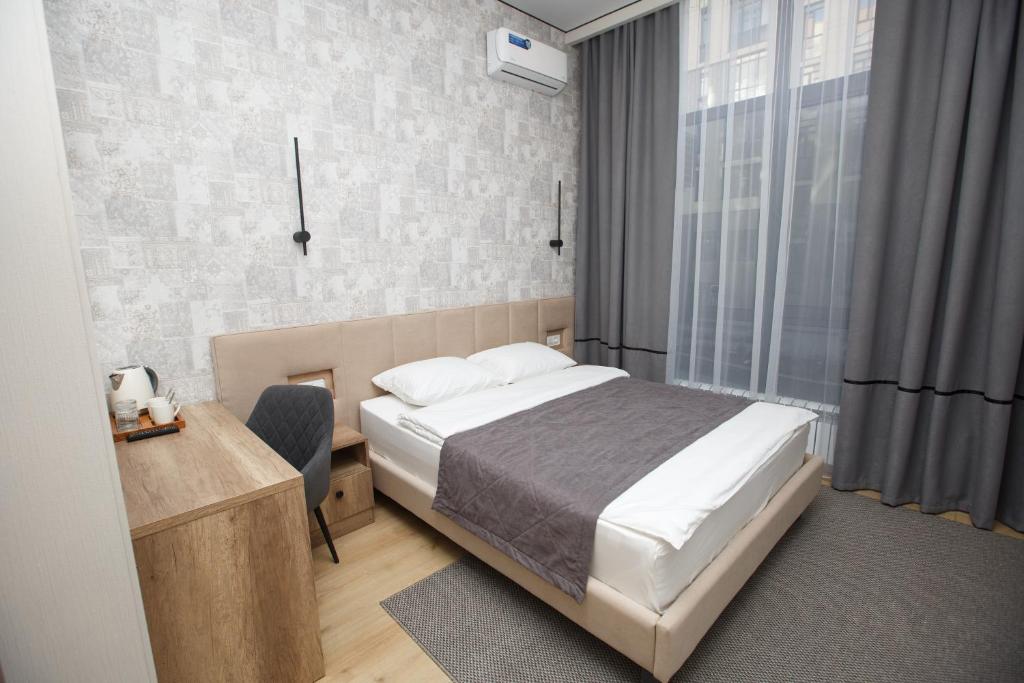 a bedroom with a bed and a desk and a window at Отель Asyl in Astana