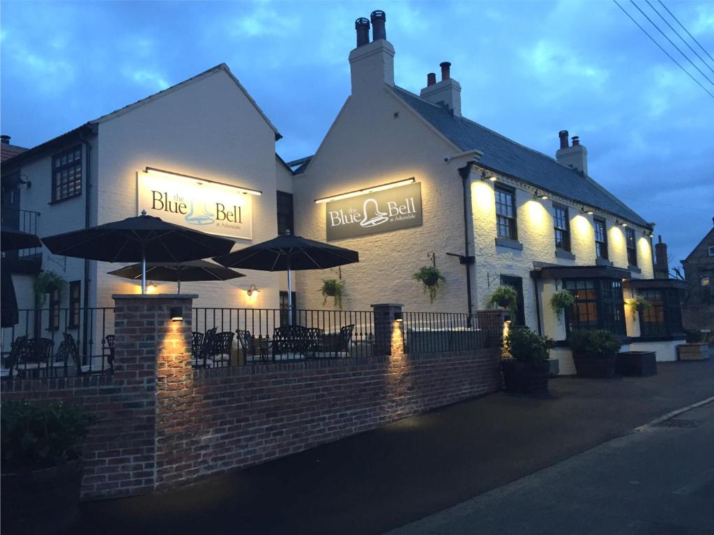 a building with tables and umbrellas in front of it at The Blue Bell at Arkendale in Knaresborough