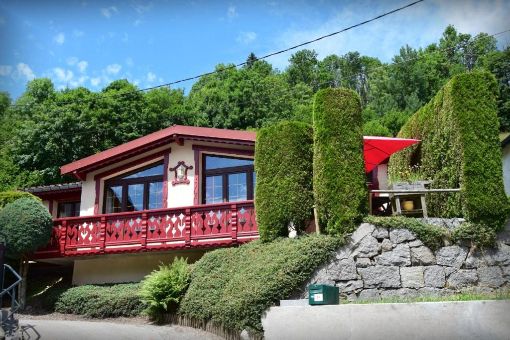 una casa con barandilla roja y árboles en Maison de style chalet individuelle Le Rouge Feigne à La Bresse, en La Bresse