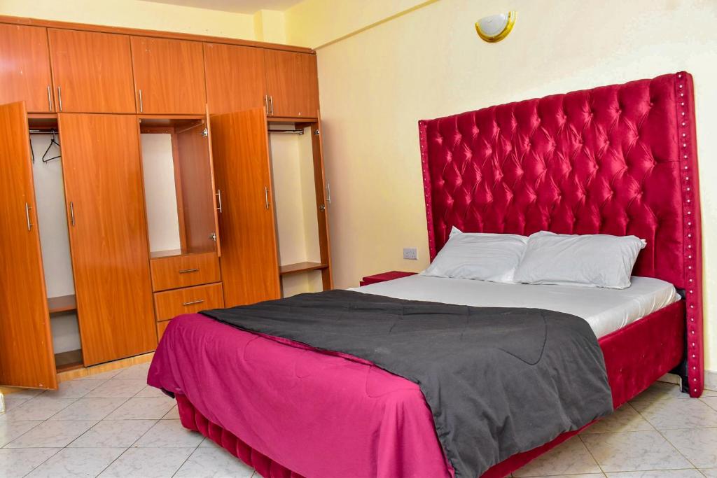 a large bed with a red headboard in a room at DESIRED 2 BEDROOM Apartment in Thika