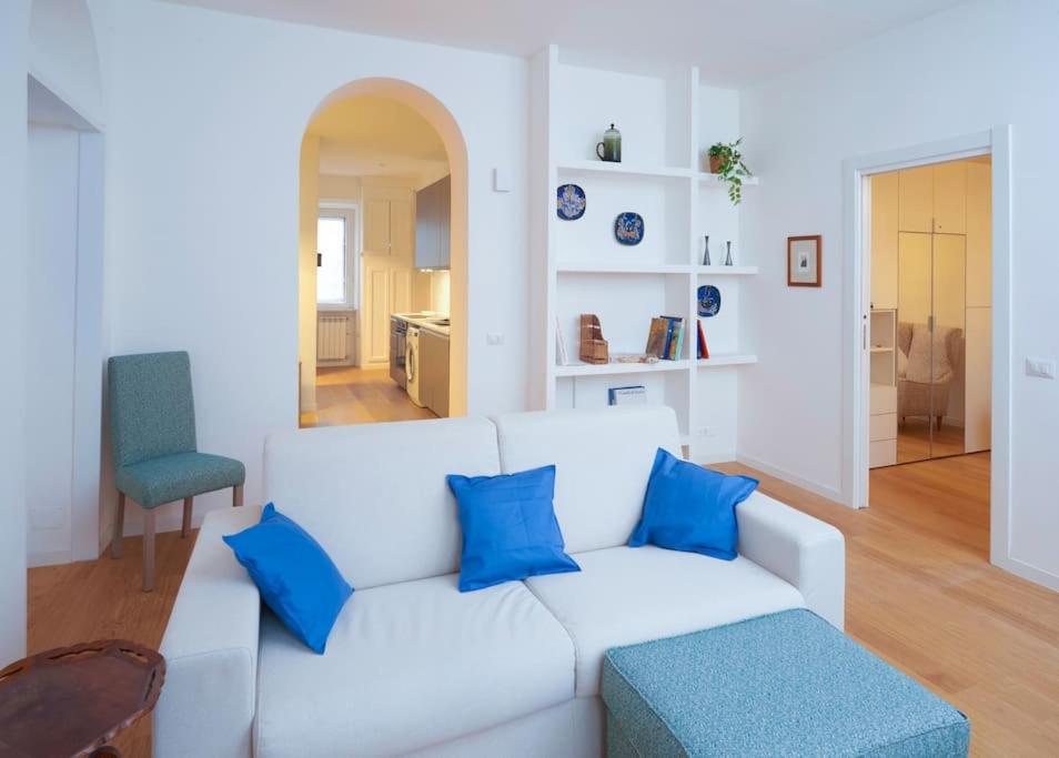 a living room with a white couch and blue pillows at Luma Apartment Navigli: Cozy and Romantic Getaway in Milan