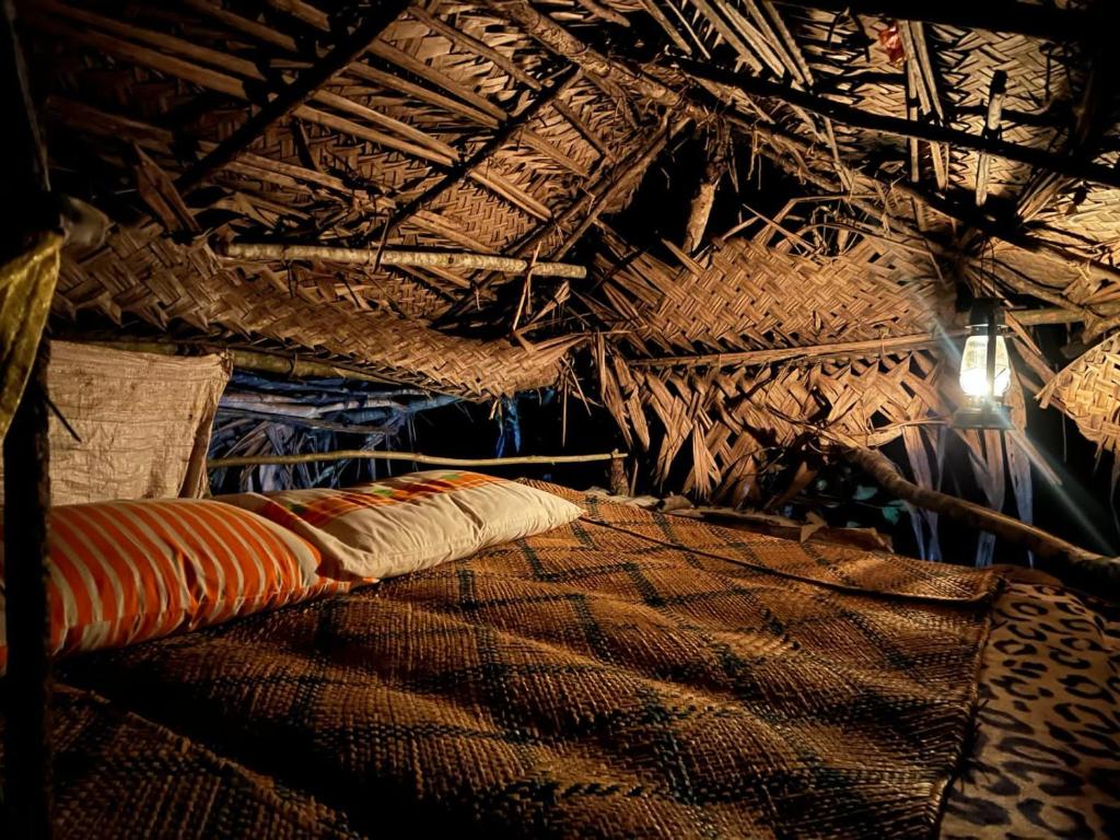 a bed in a room with a straw roof at Bulnewa Grammar International home stay/Tree-house 