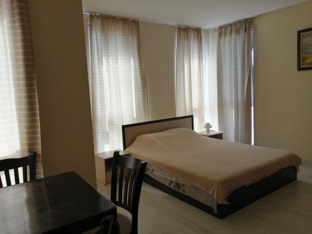 a bedroom with a bed and a table and windows at Guest House SNG in Nesebar