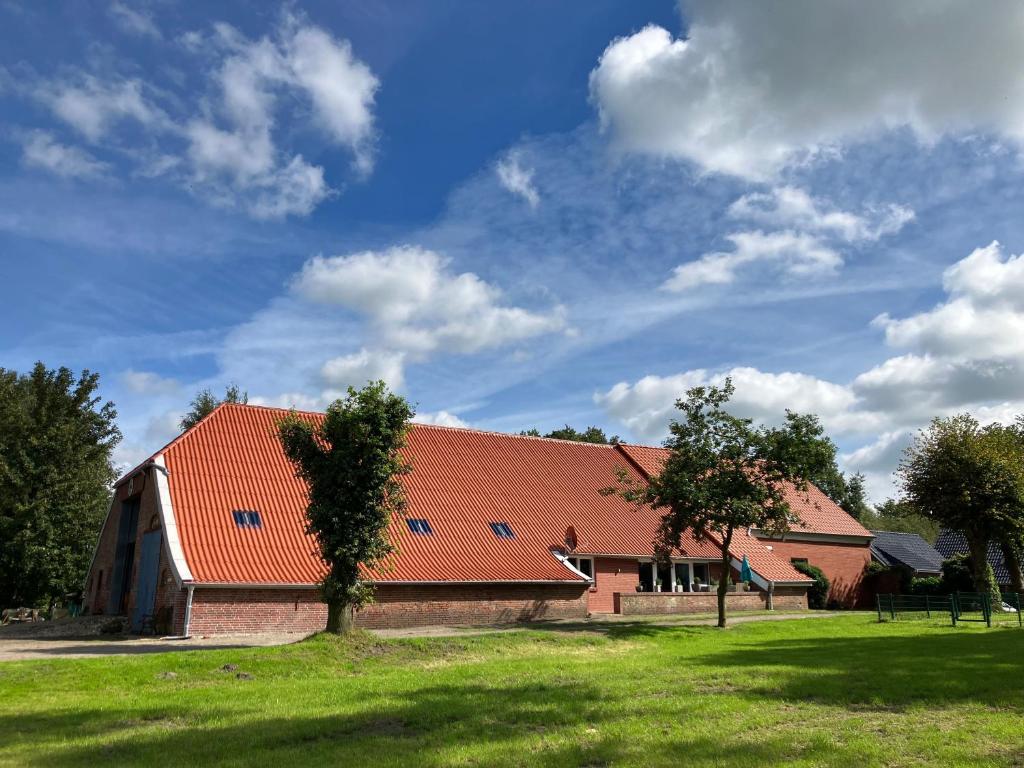 um celeiro com um telhado laranja num campo verde em Ferienwohnung Bruns em Ihlow