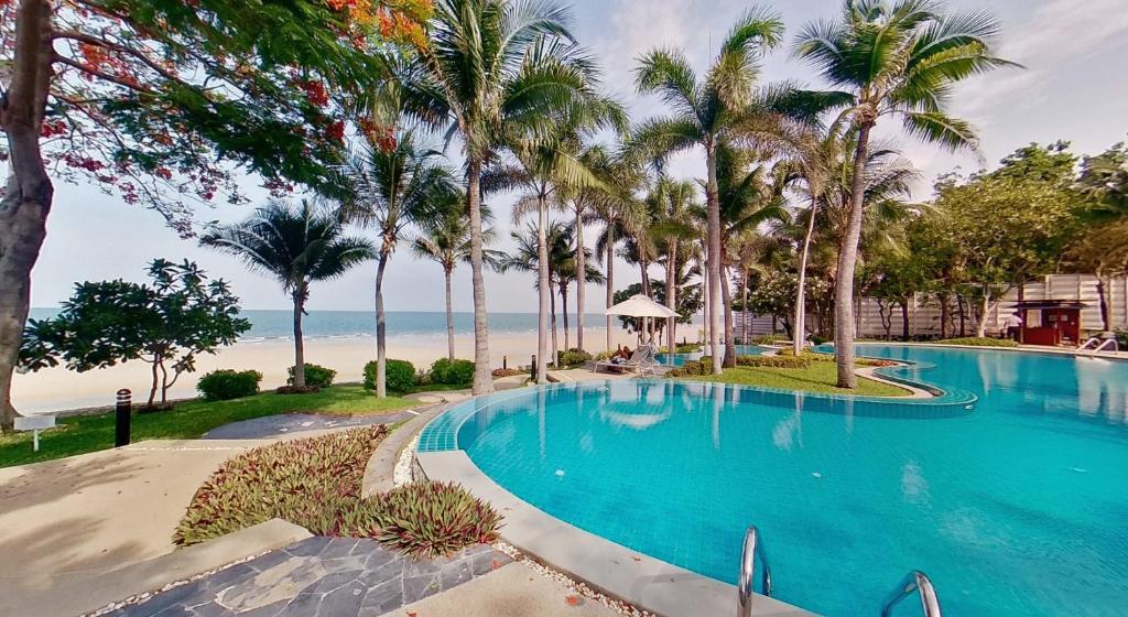 華欣的住宿－2BR Beachfront Condo in central HuaHin, Baan Saen Ploen，棕榈树和海滩的游泳池
