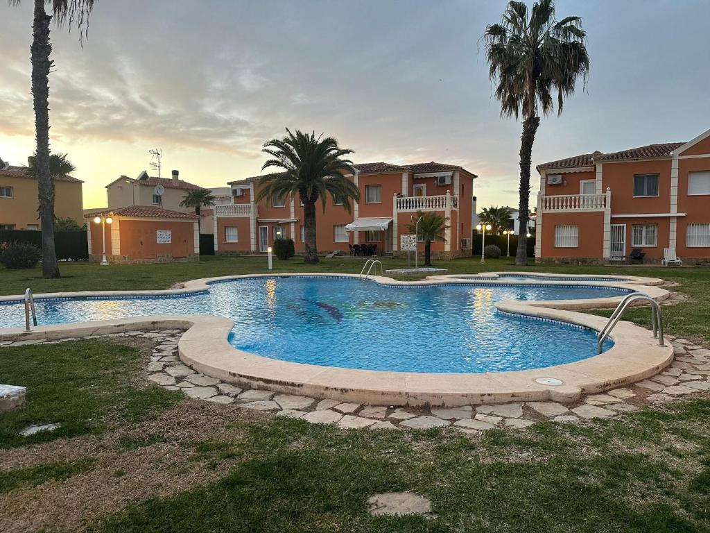 una piscina en un patio con palmeras y casas en OLIVA NOVA GOLF BEACH & RESORT Club Sevilla VI 3A, en Oliva